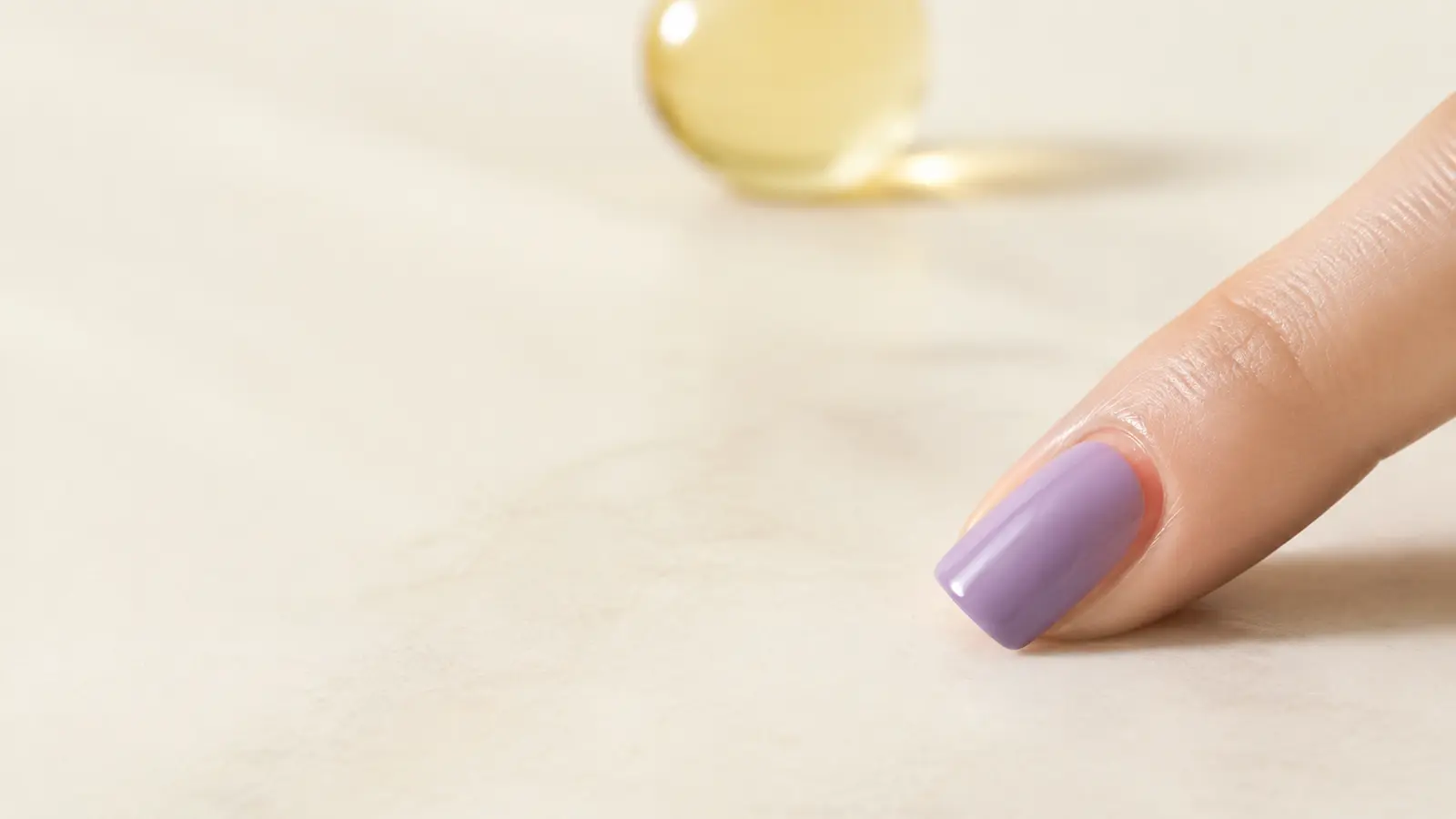 A dusty-lavender press-on laid over a natural nail during a dry fit to check whether its side coverage is sufficient.